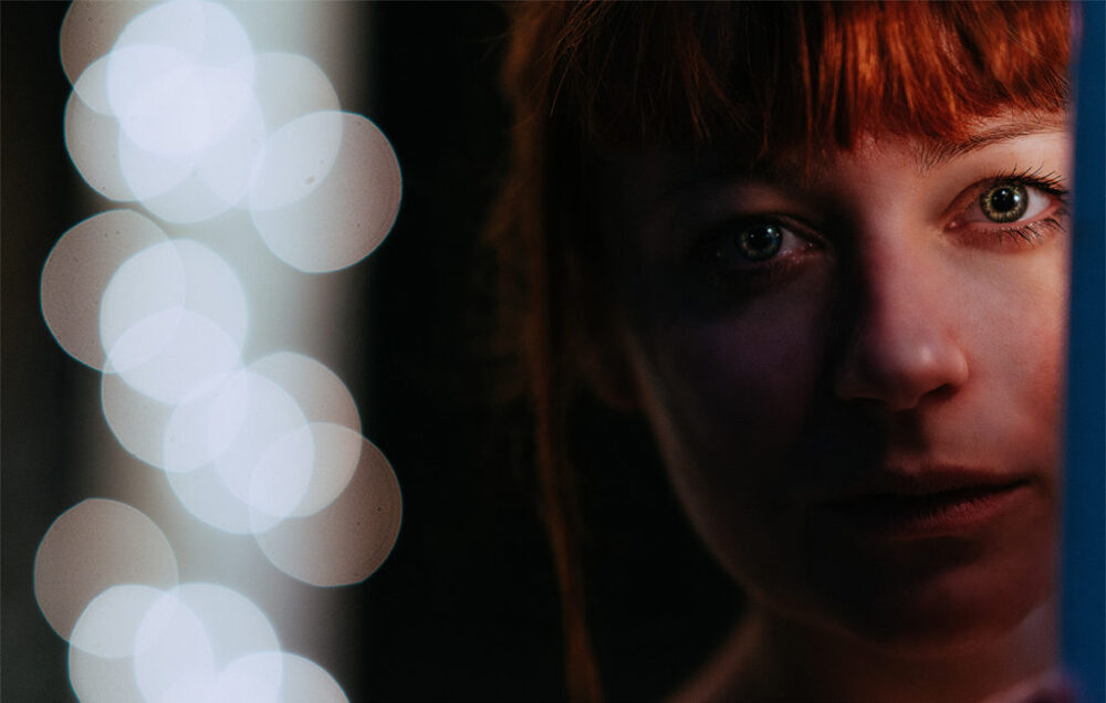 Cinematic close up of ginger woman with green eyes in the darkne